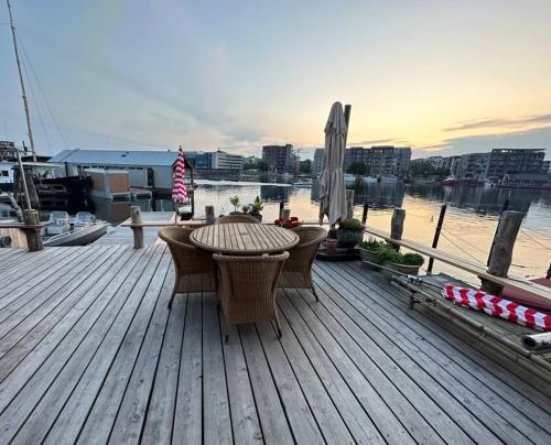 um deque de madeira com uma mesa e cadeiras num barco em Unique boathouse. em Copenhaga