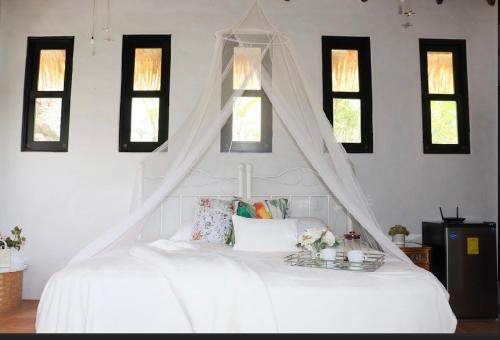 a white bed with a canopy in a room with windows at Villa La Fortuna in Filipina