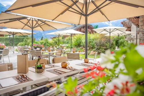 a restaurant with white tables and umbrellas at Armancette - The Leading Hotels of the World in Saint-Gervais-les-Bains