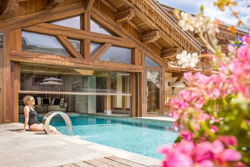 une femme assise à côté d'une piscine dans une maison dans l'établissement Armancette Hôtel, Chalets & Spa – The Leading Hotels of the World, à Saint-Gervais-les-Bains