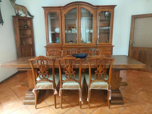 a dining room table with chairs and a wooden cabinet at Casa Valda in Fanano
