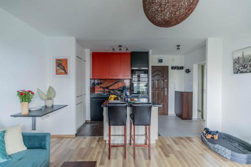 kuchnia i salon z czerwonymi szafkami i niebieską kanapą w obiekcie Pet’s House Warsaw w Warszawie
