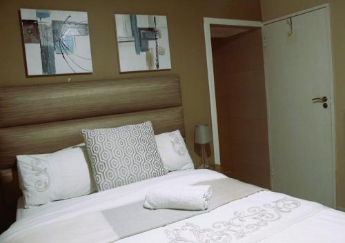 Schlafzimmer mit einem Bett mit weißer Bettwäsche und Kissen in der Unterkunft Qunu Heritage Home - Mthatha in Mthatha