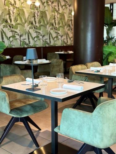 a dining room with tables and green chairs at Ramada Plaza by Wyndham Milano in Milan