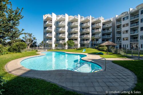 a swimming pool in front of a large apartment building at Umdloti Cabanas 32 Triplex in Umdloti