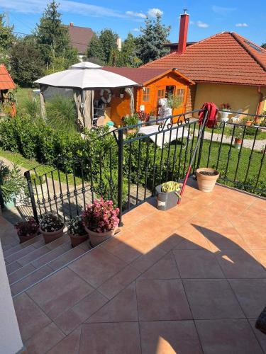 a fence with potted plants and an umbrella on a patio at Rege apartman 3 in Alsóörs
