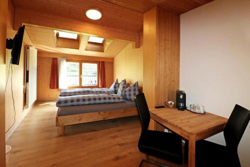 a bedroom with a bed and a wooden table at Berghotel Distelboden in Frutt
