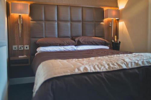a bedroom with a large bed with a large headboard at The Fort Hotel in Dundee