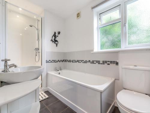 a bathroom with a tub and a sink and a toilet at Primrose Cottage in Poundstock