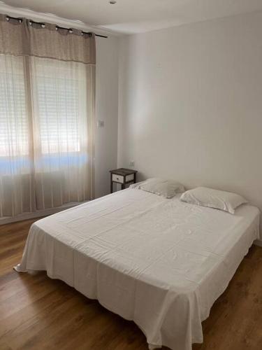 een slaapkamer met een groot wit bed met witte lakens bij maison de village in Balaruc-le-Vieux