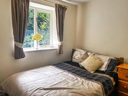 a bed sitting in a bedroom with a window at Woodside Fishery - The Mallards in Cleobury Mortimer