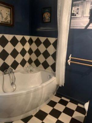 La salle de bains est pourvue d'une baignoire blanche et d'un sol en damier. dans l'établissement La maison de Fanny, à Jarnioux