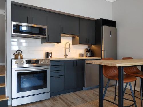 a kitchen with black cabinets and a wooden table at Chalet Détente Orford in Orford