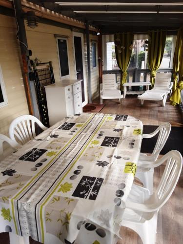 a table with white chairs and a blanket on it at mobil home tout équipé 3 chambres in Gastes