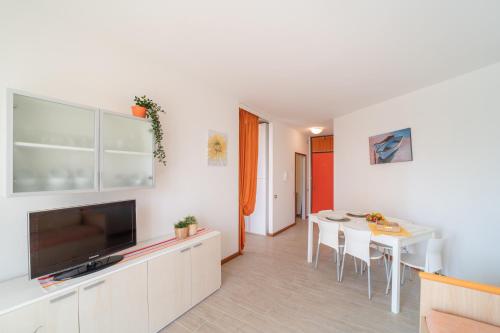 a living room with a dining room table and a television at Residenza Puerto Do Sol in Lignano Sabbiadoro