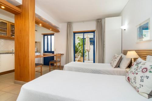 um quarto de hotel com duas camas e uma cozinha em Apartamentos Rossio Mar em Albufeira