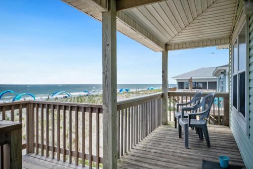 a porch with two chairs and a view of the beach at Absolute Beach by Oak Island Accommodations in Oak Island