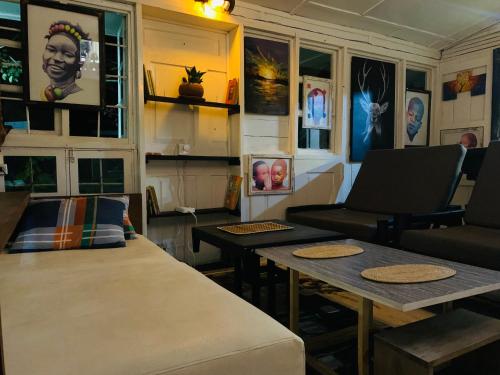 Habitación con mesas, sillas y cuadros en las paredes. en MASHA ARTS STUDIO, en Ruhengeri
