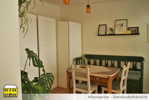 a dining room with a table and chairs and a plant at Das Gelbe Haus - Drei besondere Ferienwohnungen in Flensburg