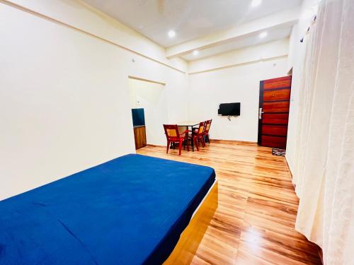 a bedroom with a blue bed and a table at VAGAMON VAGADROPS in Vagamon