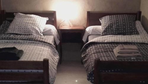 Un dormitorio con dos camas y una mesa con lámpara. en Gîte Mourtis, en Nistos