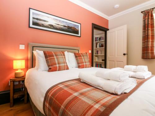 a bedroom with two beds with orange walls at The Old Laundry Cottage in Perth