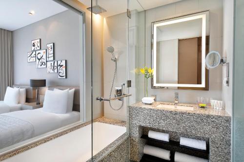 a bathroom with a shower and a bed and a sink at Le Meridien City Centre Bahrain in Manama