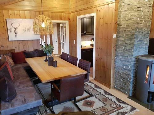 ein Esszimmer mit einem Holztisch und einem Kamin in der Unterkunft TRYSIL - Koselig norsk fjellhytte in Nybergsund