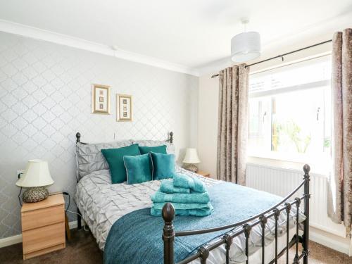 a bedroom with a bed with blue pillows and a window at Fernleigh Villa Annexe in Wisbech