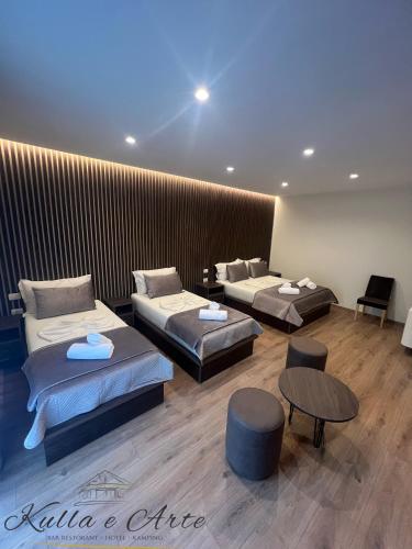 a room with three beds and two tables and chairs at Hotel Kulla e Arte in Razëm