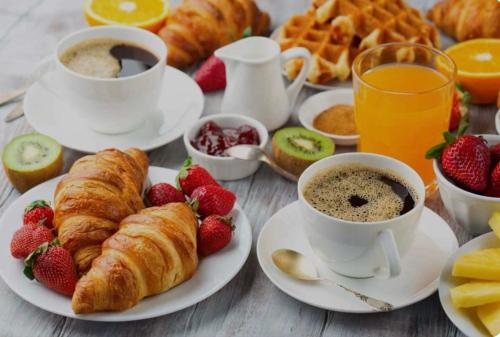 a breakfast table with croissants and cups of coffee and fruit at CD Romanello (Mura S. Cataldo) in Barletta