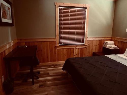a bedroom with a bed and a desk and a window at Alwar House: A mountain paradise in Piney Creek