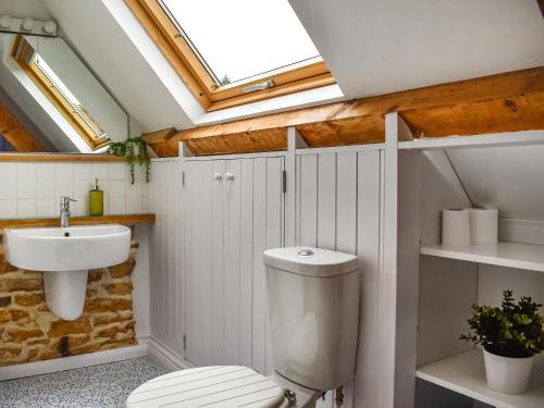 a bathroom with a toilet and a sink and a skylight at The Telephone Box At The Old Post Office in North Perrott