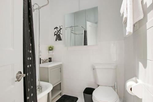 a white bathroom with a toilet and a sink at City Charm 2BR Apartment - Clark 4 in Chicago