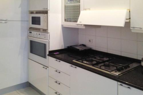 a kitchen with white cabinets and a stove top oven at Casa de Praia da Zezinha in Costa da Caparica