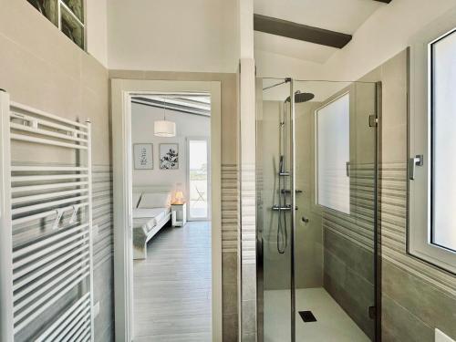 a bathroom with a walk in shower and a glass door at Villa Noga Rooms in Selargius