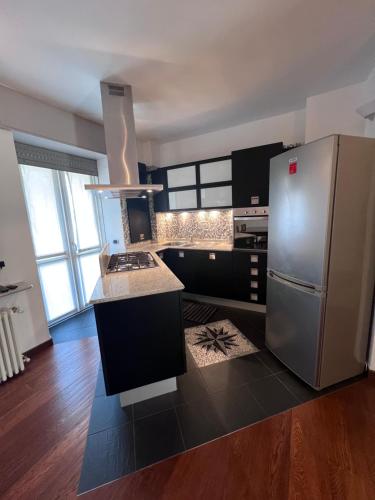 a kitchen with a stainless steel refrigerator and black cabinets at Casa vacanze Attico sul lago di Lecco, a due passi dal centro con posto auto in Lecco