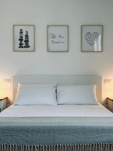 a bed in a bedroom with two pictures on the wall at Villa Noga Rooms in Selargius