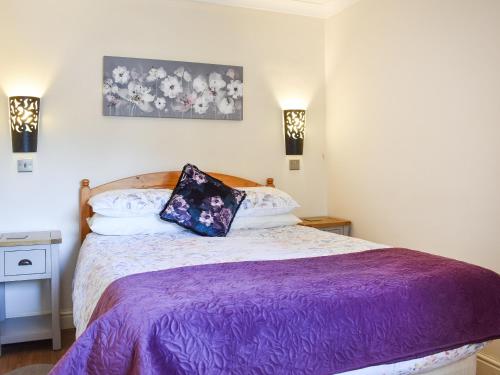 a bedroom with a bed with a purple blanket at Teddys Cottage - Uk44685 in Burnopfield