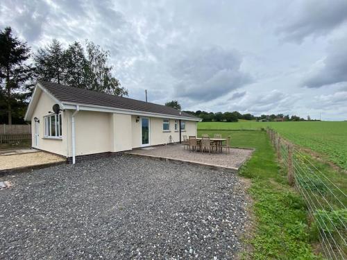 a small white building with a picnic table in a field at Cosy bungalow with views, walks, garden & parking. in Worcester