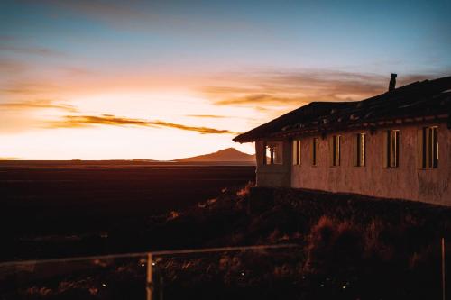an old building with the sunset in the background at Hotel de Sal Luna Salada in Colchani