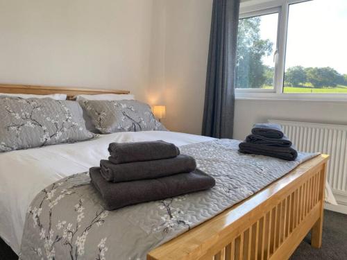 a bedroom with a bed with towels on it at Cosy bungalow with views, walks, garden & parking. in Worcester
