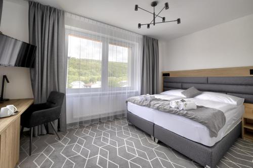 Schlafzimmer mit einem Bett, einem Schreibtisch und einem Fenster in der Unterkunft Typton hotel&spa in Medzilaborce