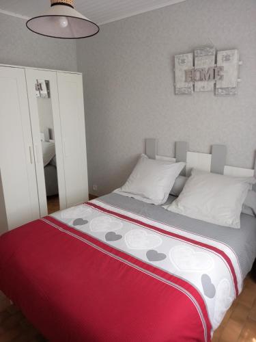 un lit dans une chambre avec une couverture rouge et grise dans l'établissement Location vacances Ruoms Ardèche, à Ruoms