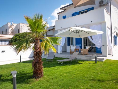 a palm tree and an umbrella in front of a house at Villa Marisa - Villa di Lusso Fronte Spiaggia in Cittadella del Capo