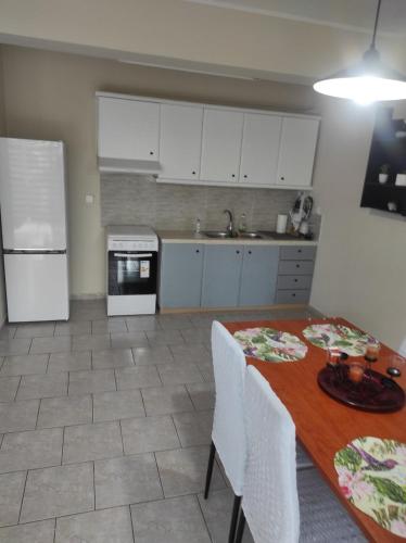 uma cozinha com uma mesa de madeira e armários brancos em Nikos Apartments em Amarinthos