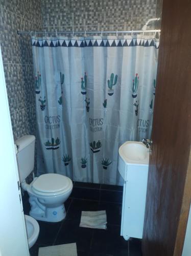 a bathroom with a toilet and a sink and a shower curtain at Casa de campo in Colón