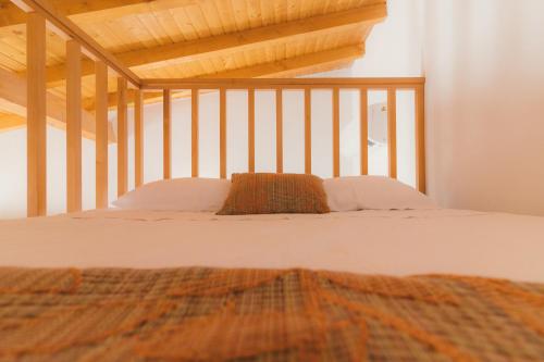 Cette chambre comprend un lit avec des draps blancs et un plafond en bois. dans l'établissement CHALÉ, à Alijó