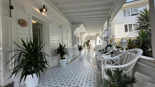 hi HOTEL IVY BÜYÜKADA في جزر الأمراء: شرفة مع كراسي بيضاء ونباتات على مبنى