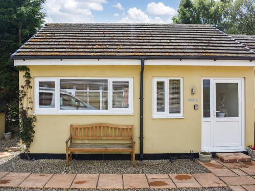 una casa amarilla con un banco delante en Gracies Cottage - Uk44686 en Burnopfield